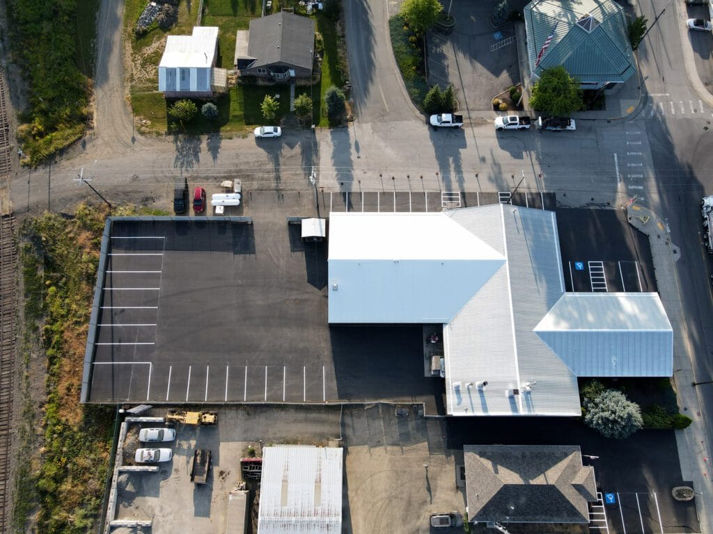 Freshly sealcoated and striped auto body shop parking lot showing clean black asphalt and bright new parking lines after professional resurfacing
