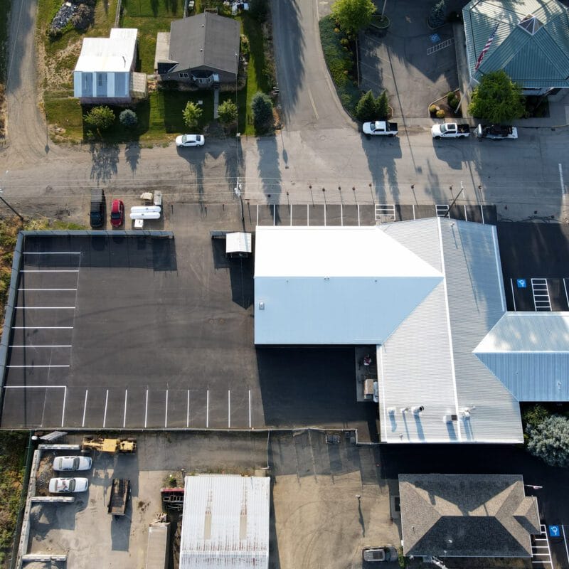 Freshly sealcoated and striped auto body shop parking lot showing clean black asphalt and bright new parking lines after professional resurfacing