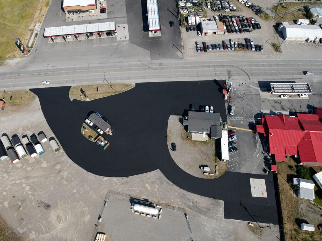 Aerial view of freshly sealcoated commercial asphalt lot in Spokane area showing smooth black surface ready for summer protection