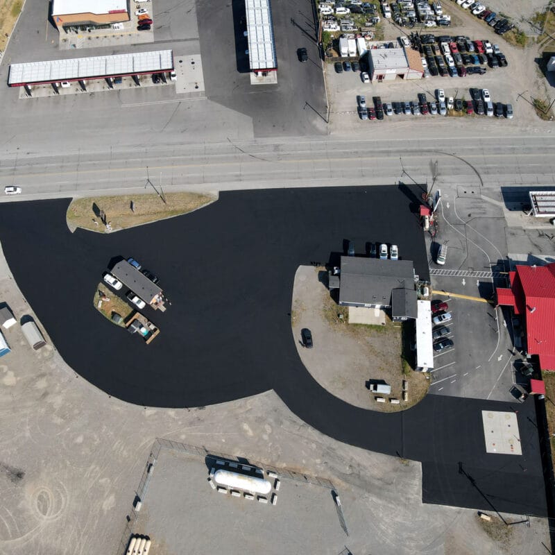 Aerial view of freshly sealcoated commercial asphalt lot in Spokane area showing smooth black surface ready for summer protection
