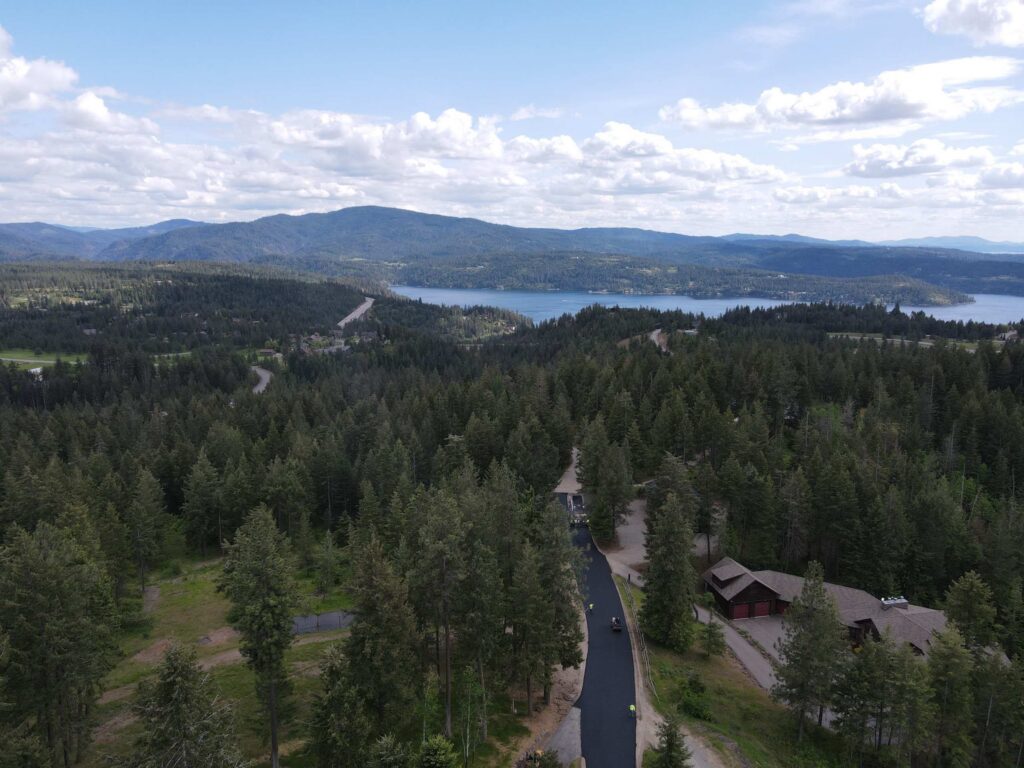 private-road-paving-coeur-dalene-idaho-04 Drone view of completed private road paving project overlooking the forests and lake near Coeur d'Alene, Idaho.