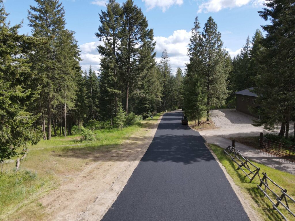 private-road-paving-coeur-dalene-idaho-03 Newly paved residential access road winding through a wooded neighborhood in Coeur d'Alene, Idaho.