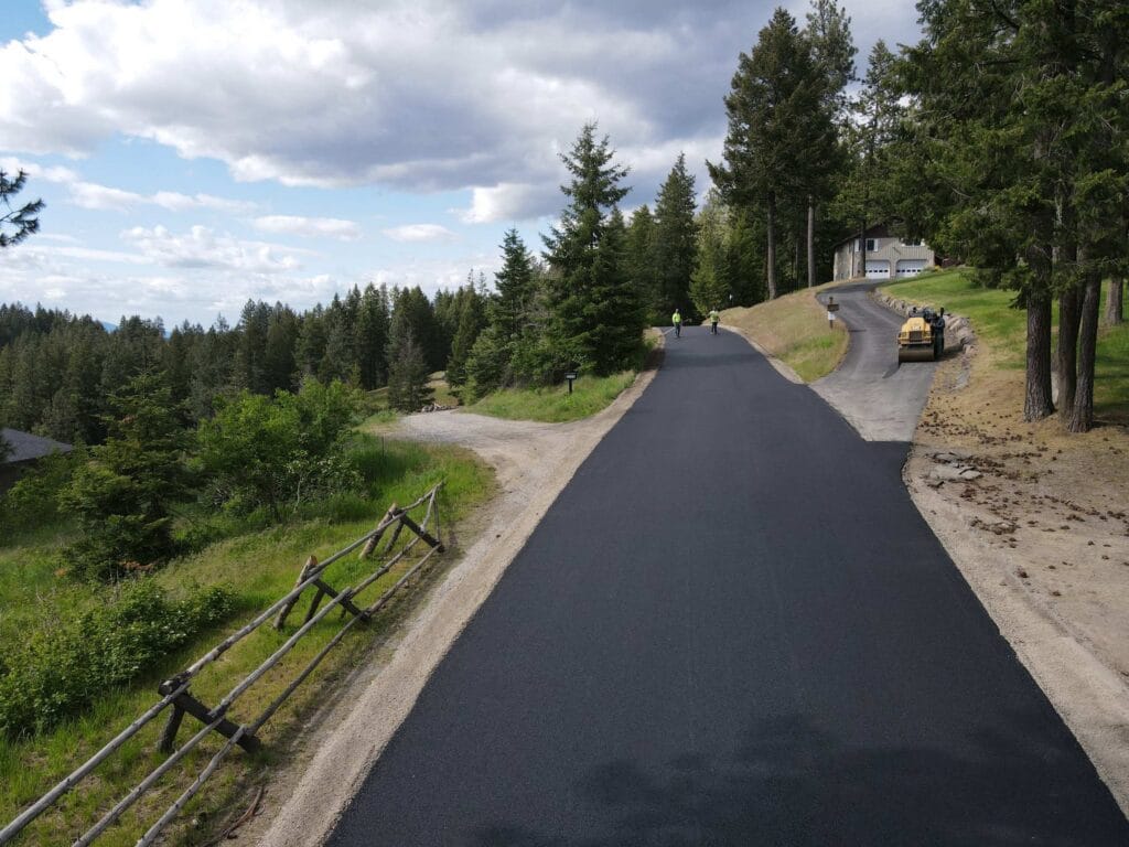 private-road-paving-coeur-dalene-idaho-01 Freshly paved private road leading to residential homes in Coeur d'Alene, Idaho after grading and 3-inch asphalt paving by Asphalt Pros USA.