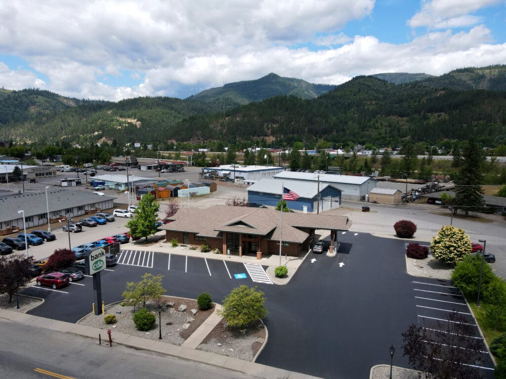 Aerial view of a newly paved Bank CDA parking lot in North Idaho with marked parking spaces, drive lanes, and surrounding mountains