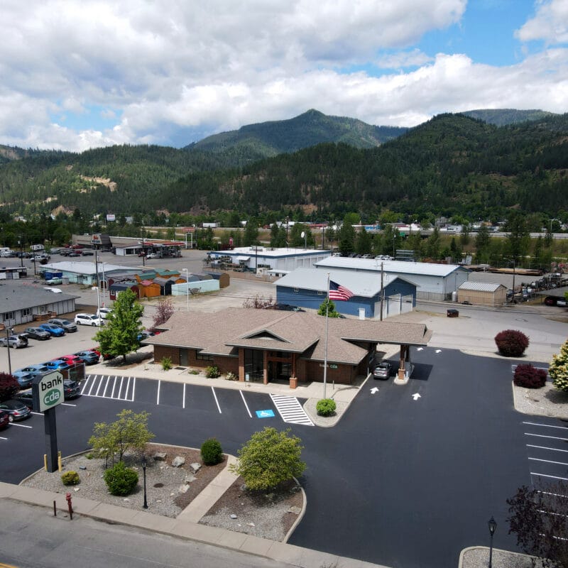 Aerial view of a newly paved Bank CDA parking lot in North Idaho with marked parking spaces, drive lanes, and surrounding mountains